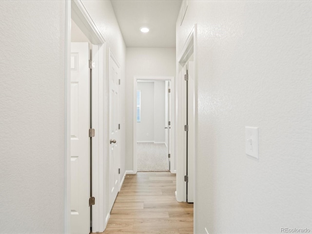 hallway with a textured wall and light wood-style flooring