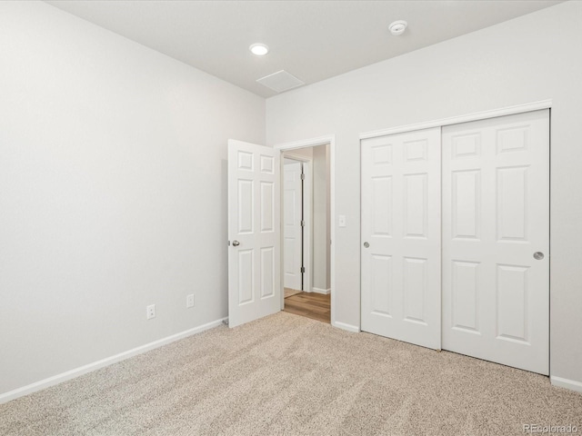 unfurnished bedroom with light carpet, baseboards, and a closet