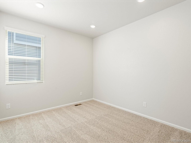 empty room featuring carpet floors, recessed lighting, visible vents, and baseboards