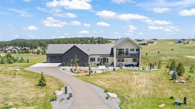 view of front facade featuring a garage, a balcony, and a rural view