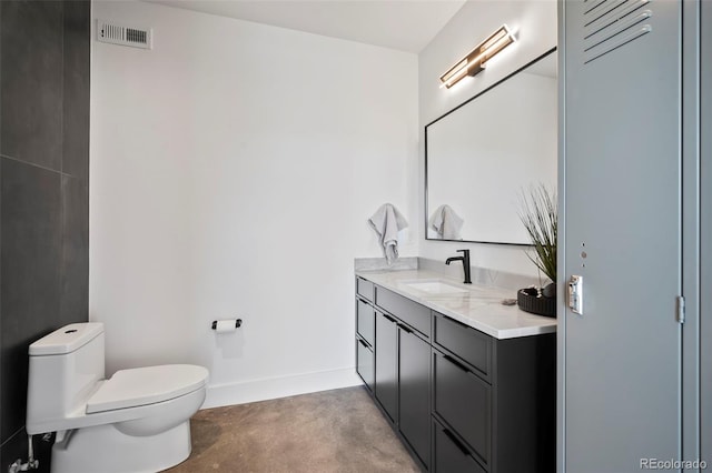 bathroom featuring vanity, concrete flooring, and toilet