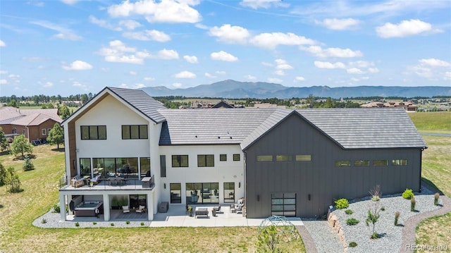 back of property with an outdoor living space, a yard, a mountain view, and a patio