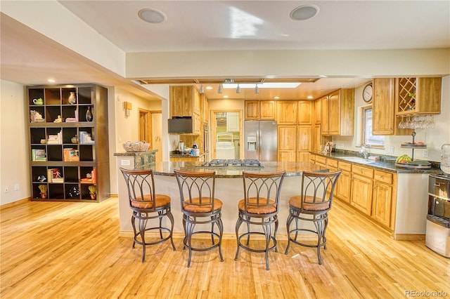 kitchen with a breakfast bar, a kitchen island, light wood-type flooring, and appliances with stainless steel finishes