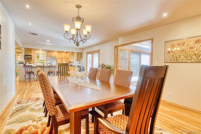 dining area with light hardwood / wood-style floors and an inviting chandelier