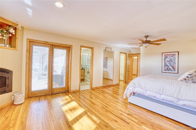 bedroom featuring ensuite bath, heating unit, access to outside, ceiling fan, and wood-type flooring