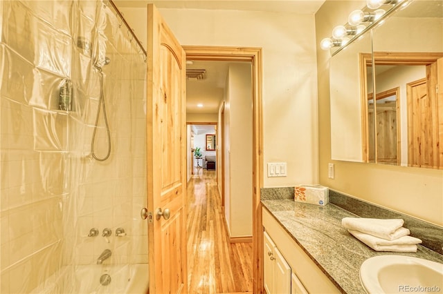 bathroom featuring hardwood / wood-style floors, vanity, and tiled shower / bath