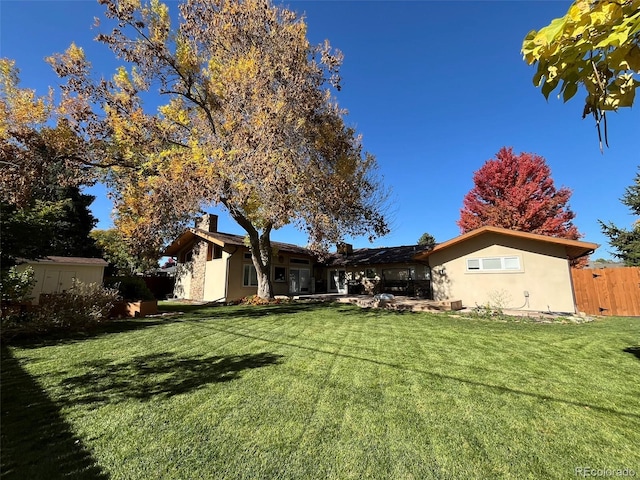 rear view of property featuring a storage unit and a yard