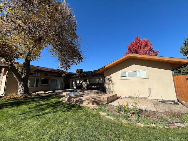 rear view of house featuring a lawn and a patio