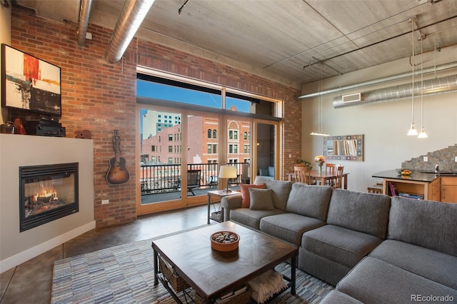 living room featuring a towering ceiling and brick wall