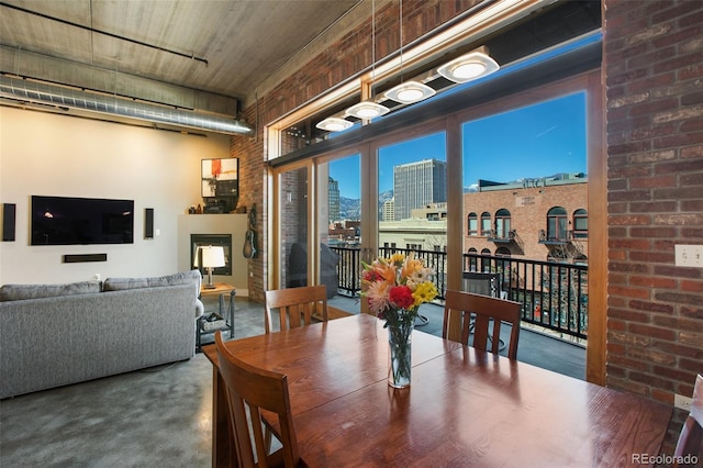 dining space with a towering ceiling and brick wall