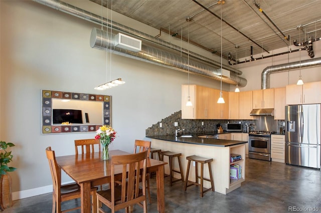 kitchen with light brown cabinets, a high ceiling, tasteful backsplash, kitchen peninsula, and stainless steel appliances