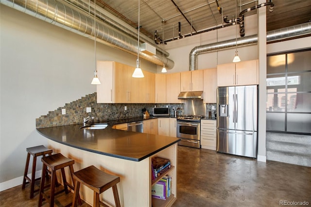 kitchen featuring kitchen peninsula, appliances with stainless steel finishes, a towering ceiling, and light brown cabinetry