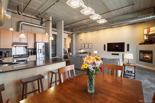 dining area featuring sink, a high ceiling, and concrete floors