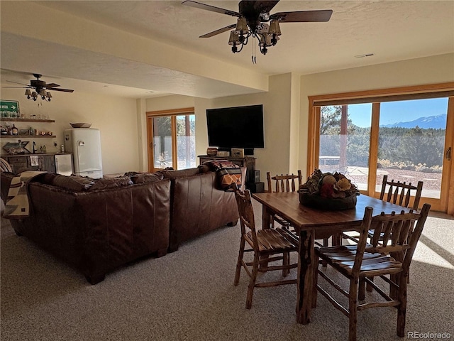 carpeted dining space with a textured ceiling and ceiling fan