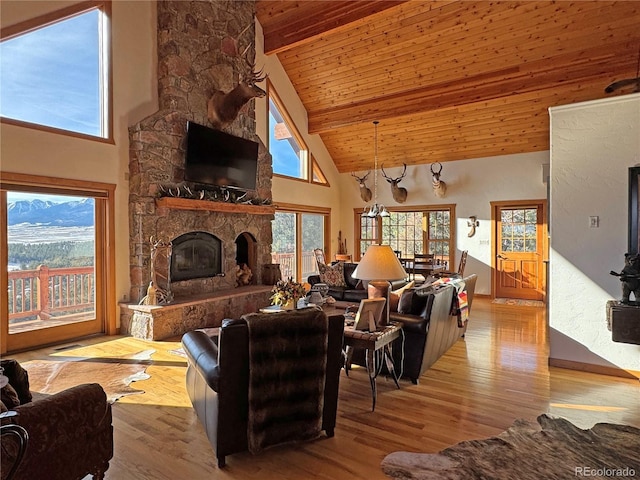 living room with wooden ceiling, a stone fireplace, light hardwood / wood-style flooring, high vaulted ceiling, and a notable chandelier