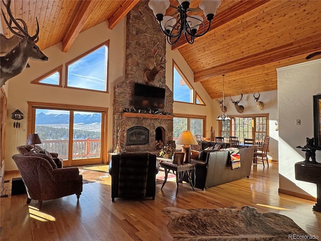 living room featuring high vaulted ceiling, a stone fireplace, beam ceiling, wood-type flooring, and a chandelier