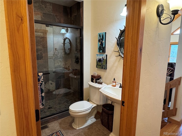 bathroom featuring toilet and a shower with shower door