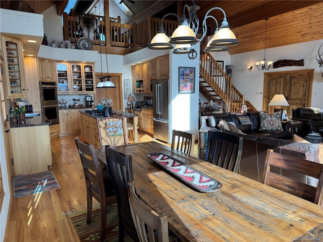 dining space featuring wooden ceiling, high vaulted ceiling, an inviting chandelier, beam ceiling, and light hardwood / wood-style floors