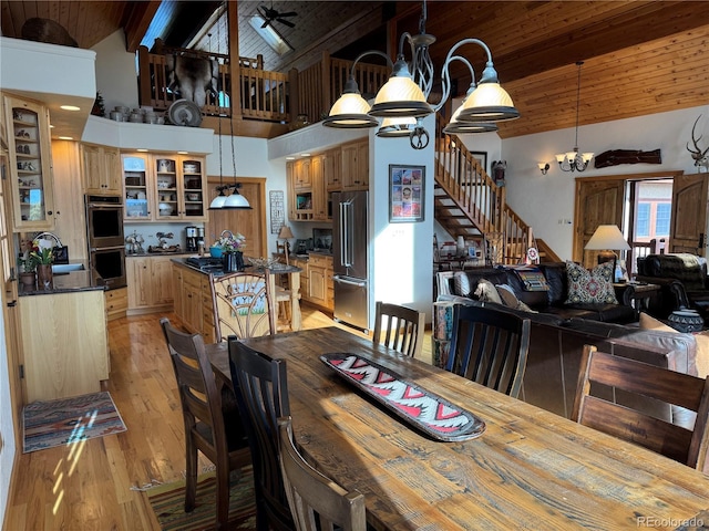 dining area with high vaulted ceiling, ceiling fan with notable chandelier, light hardwood / wood-style flooring, beamed ceiling, and wood ceiling