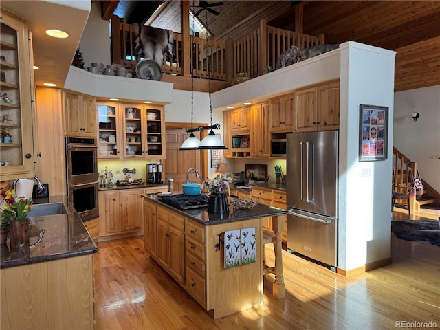 kitchen featuring decorative light fixtures, a kitchen island, stainless steel appliances, and a high ceiling