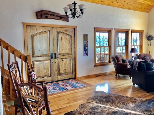 foyer with an inviting chandelier, light wood-type flooring, lofted ceiling, and wooden ceiling