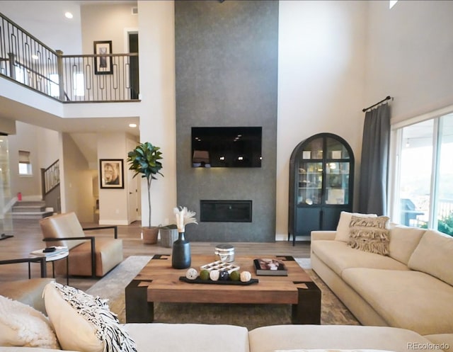 living room with stairs, a high ceiling, wood finished floors, and a fireplace