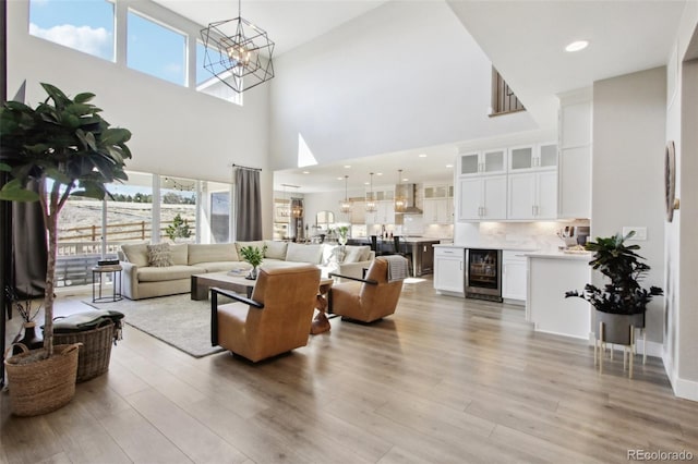 living area featuring beverage cooler, a notable chandelier, light wood-style flooring, and recessed lighting