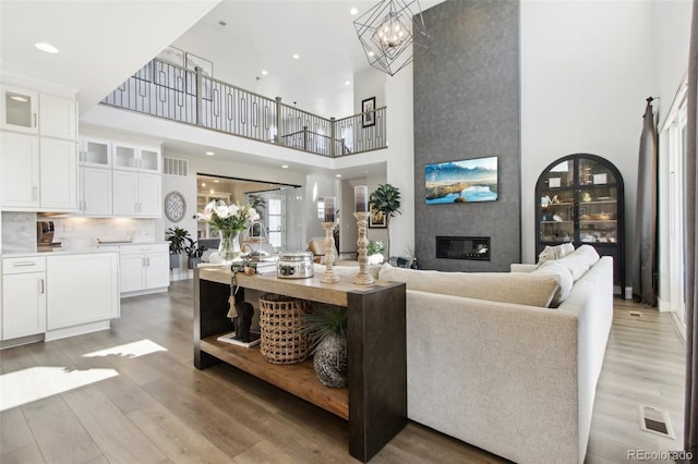 living area with a high ceiling, a fireplace, visible vents, and light wood finished floors