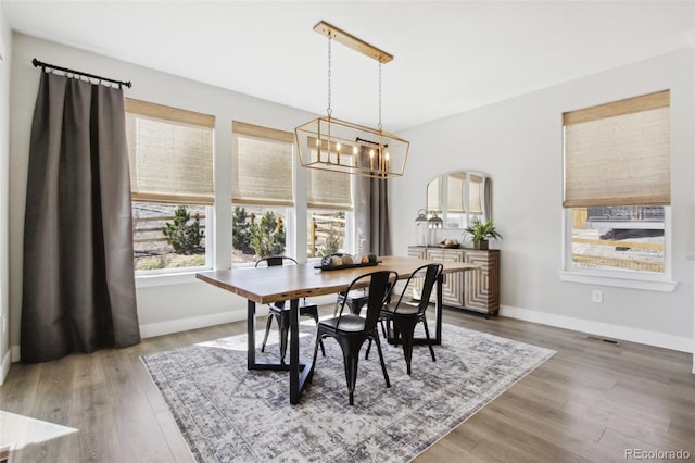 dining space featuring baseboards, a notable chandelier, and wood finished floors