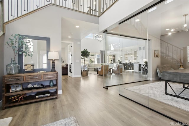 foyer featuring stairway, baseboards, a towering ceiling, and wood finished floors