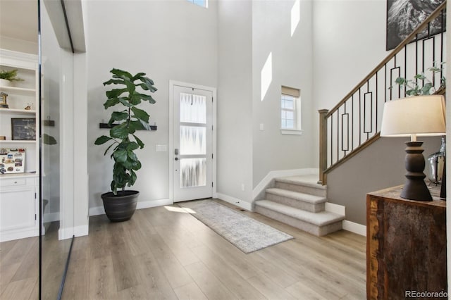 foyer with stairs, baseboards, and wood finished floors