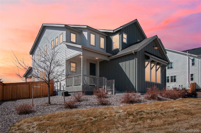 view of front facade featuring a porch, board and batten siding, and fence