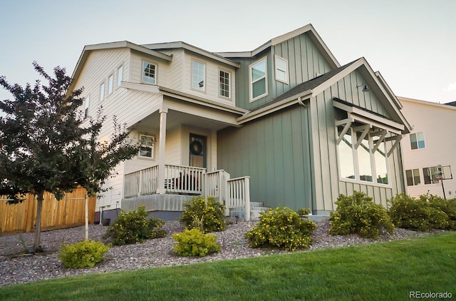 view of front facade with covered porch, board and batten siding, and fence