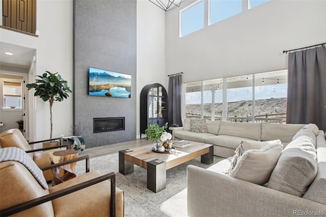 living area with a towering ceiling, wood finished floors, and a fireplace