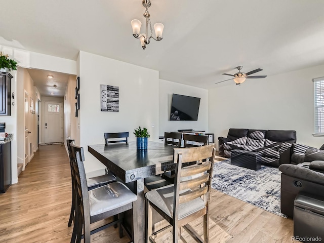 dining area with light hardwood / wood-style flooring and ceiling fan with notable chandelier