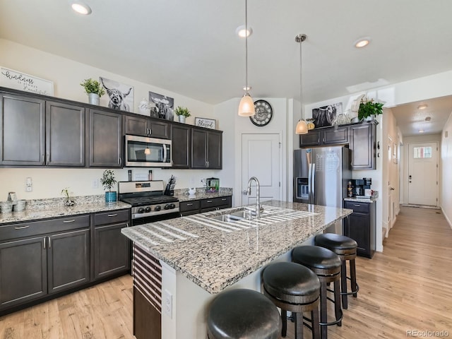 kitchen featuring a breakfast bar area, a kitchen island with sink, hanging light fixtures, and stainless steel appliances