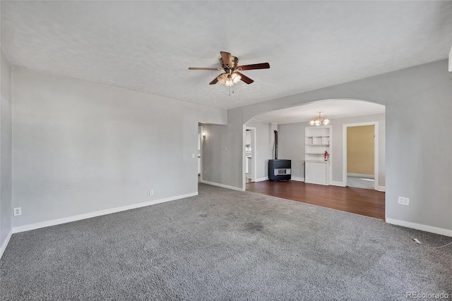 unfurnished living room with ceiling fan, dark carpet, a textured ceiling, and built in features