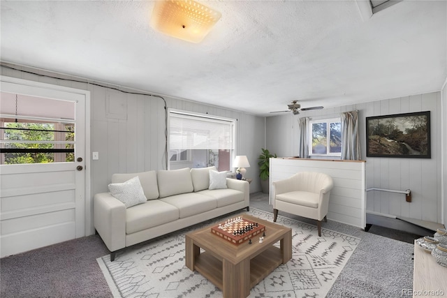 carpeted living room featuring ceiling fan and a textured ceiling