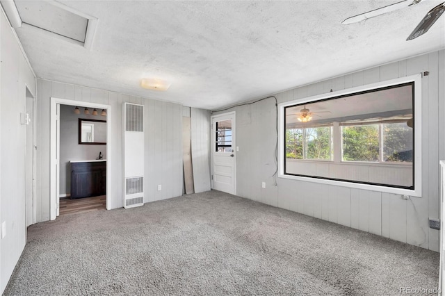 unfurnished bedroom featuring ensuite bath, carpet floors, and a textured ceiling