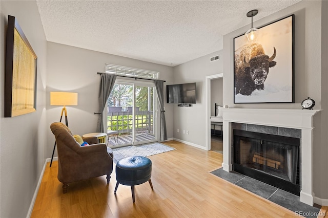 7452 Singing Hills Dr, Boulder, CO 80301 - living area with a textured ceiling, wood finished floors, a tiled fireplace, and baseboards