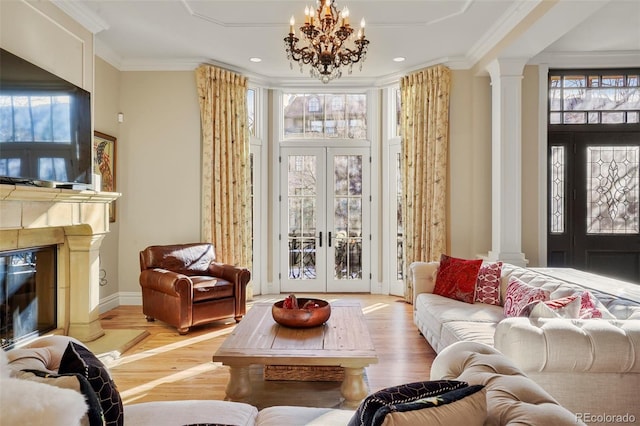 interior space with french doors, a fireplace, crown molding, a notable chandelier, and ornate columns