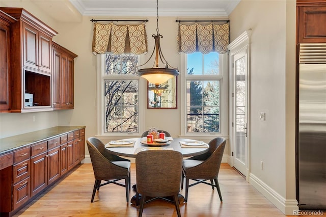 dining room with light wood-style flooring, ornamental molding, and baseboards