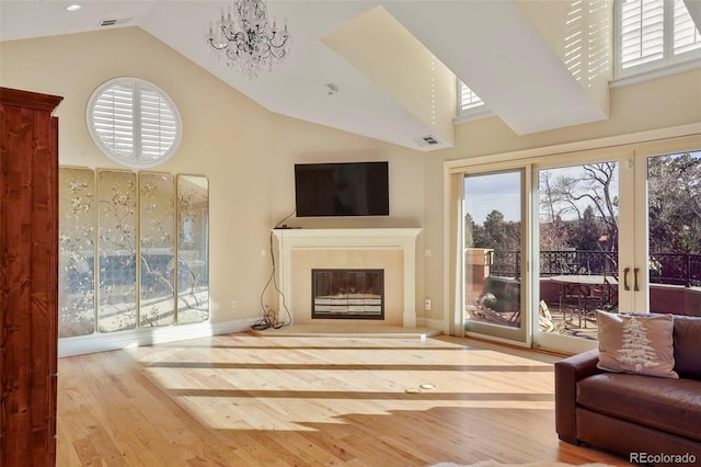 living room featuring high vaulted ceiling, a chandelier, wood finished floors, and a tile fireplace