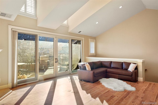 living area with visible vents, a wealth of natural light, and wood finished floors