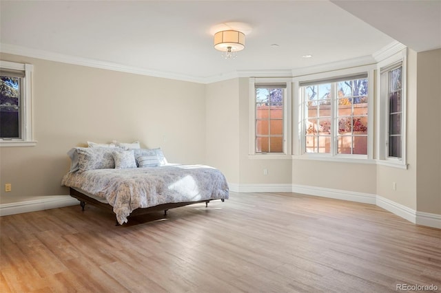 bedroom featuring ornamental molding, wood finished floors, and baseboards