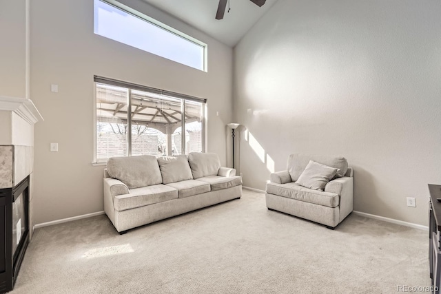 carpeted living room with high vaulted ceiling, ceiling fan, and a tiled fireplace