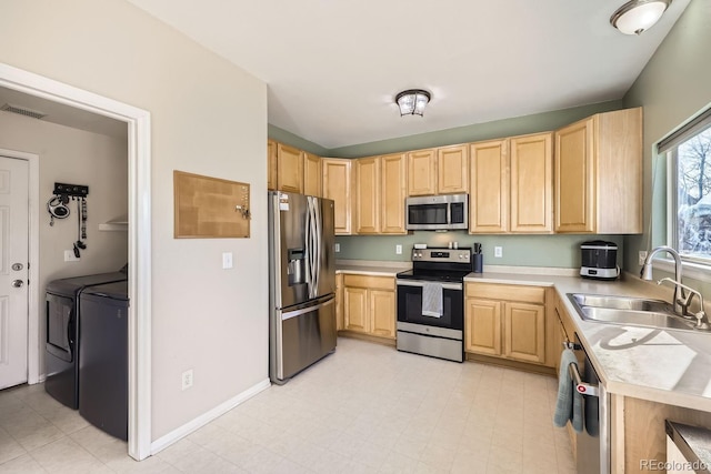 kitchen with washing machine and dryer, appliances with stainless steel finishes, light brown cabinets, and sink