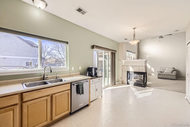 kitchen featuring decorative light fixtures, dishwasher, sink, and a fireplace