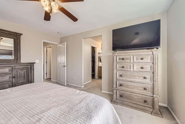 bedroom with light carpet, ceiling fan, and a walk in closet