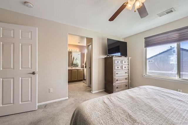 bedroom featuring ceiling fan, connected bathroom, and light carpet